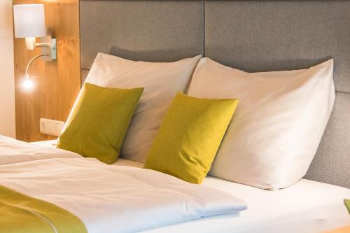 a bed with white pillows and yellow pillows at Berggasthof Christernreith in Maria Alm am Steinernen Meer