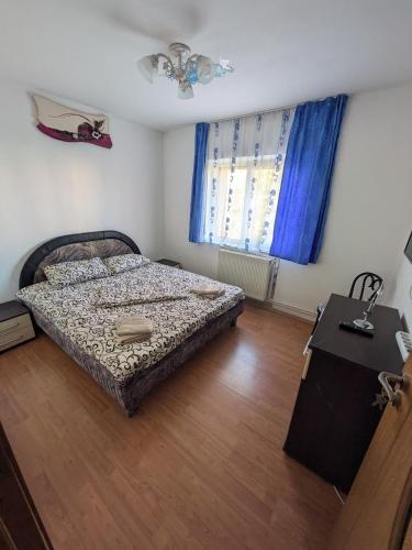 a bedroom with a bed and a window with blue curtains at Noua Apartment in Braşov