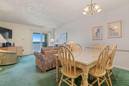 a dining room with a table and chairs and a couch at Oceanfront 2 Bedroom Condo at Golden Strand in Kill Devil Hills