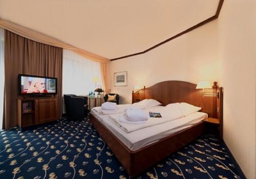 ein Hotelzimmer mit einem Bett und einem Flachbild-TV in der Unterkunft Hotel Deichgraf in Cuxhaven