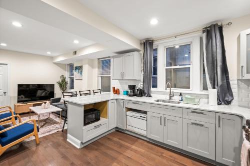 a kitchen with white cabinets and a living room at Spacious 3-Bedroom Apt in the Heart of Philly in Philadelphia
