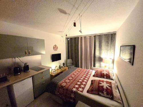 une chambre avec un lit, un bureau et une fenêtre dans l'établissement Studio avec balcon vue MontBlanc et parking gratuit le nid daigle, à Chamonix-Mont-Blanc