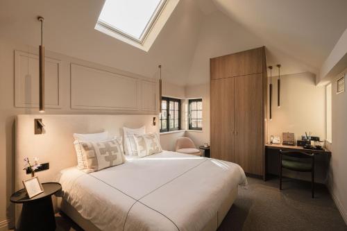 a bedroom with a large white bed and a desk at Boutiquehotel Le Foulage - adults only in Bruges