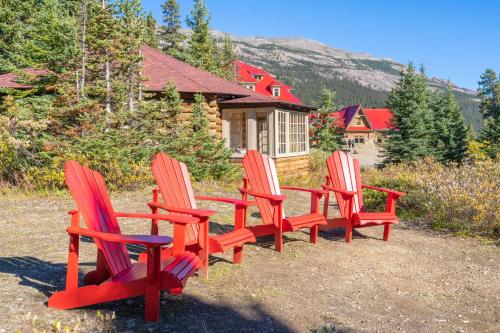 four red chairs sitting in front of a cabin at The Lodge at Bow Lake in Lake Louise
