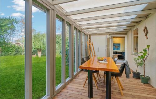a screened in porch with a wooden table and glass doors at Awesome Home In Føllenslev With Wifi in Føllenslev