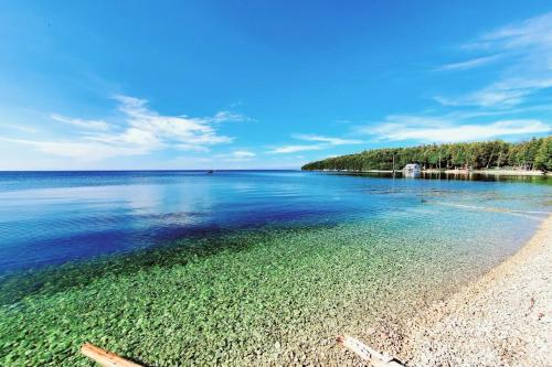 a beach with clear water and trees in the background at Bird's Nest - Above Bakery Cozy Studio, Perfect for Couples! in Sister Bay