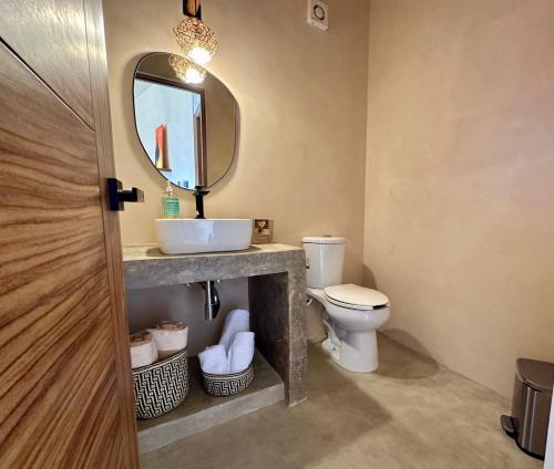 a bathroom with a sink and a toilet with a mirror at Chichén 27 Departamentos nuevos con piscina cerca de Ferry a Isla Mujeres in Cancún