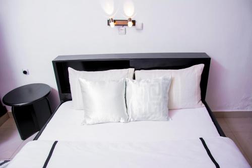 a bed with a black headboard and white pillows at Ibuye Villa Holiday Home in Nyakinama