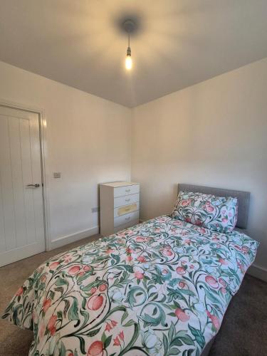 a bedroom with a bed with a floral comforter at Hazel Crescent in Burton upon Trent