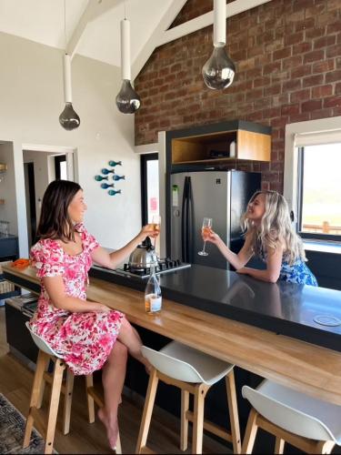 two girls sitting at a kitchen counter drinking wine at Witsand Whalecliff accommodation in Witsand