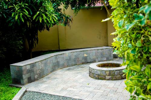a stone retaining wall with a fire pit in a yard at Ibuye Villa Holiday Home in Nyakinama