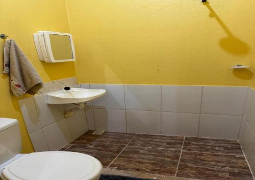 a bathroom with a white toilet and a sink at Casa Amarela in Presidente Figueiredo
