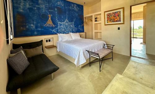 a bedroom with a bed and a chair and a couch at Chichén 27 Departamentos nuevos con piscina cerca de Ferry a Isla Mujeres in Cancún