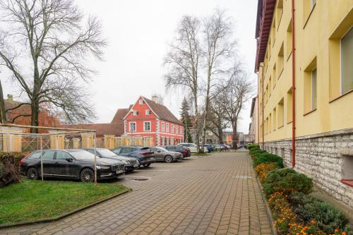 a street with cars parked next to a building at Kahe magamistoaga südalinna korter in Pärnu