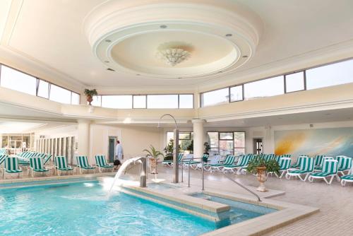 a pool in a hotel with green and white chairs at Hotel Apollo Terme in Montegrotto Terme