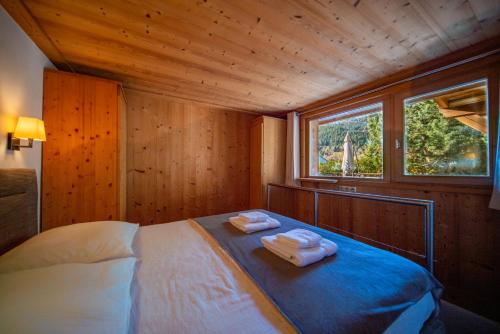 una camera da letto con un letto con due asciugamani sopra di Appartement de prestige dans chalet Novalsia à Méribel avec sauna a Méribel