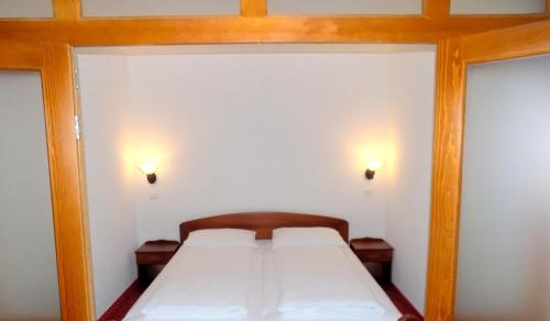 a bed in a small room with two lights at Hotel Knez in Kupres