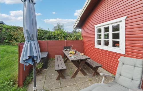 a picnic table and an umbrella next to a red building at 2 Bedroom Cozy Home In Allinge in Allinge