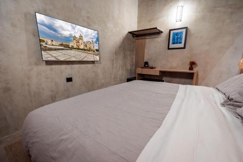 a bedroom with a white bed and a picture on the wall at Casa 1800 Oaxaca Boutique Hotel City Center based in Oaxaca City