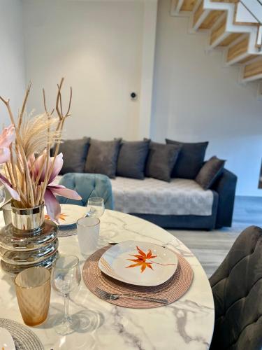 a table with two plates and a vase with flowers on it at Cool Loft in Tríkala