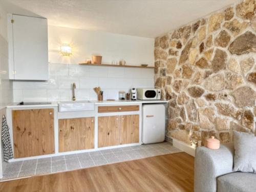 a kitchen with a sink and a stone wall at Superbe Maison - Bain Chaud ou Froid & Cinema - Cap d'Agde in Cap d'Agde