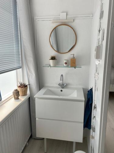 a bathroom with a white sink and a mirror at Lola's Beachhouse in Noordwijk aan Zee
