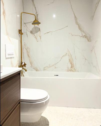 a white bathroom with a toilet and a bath tub at La maison du luxe in Ris-Orangis
