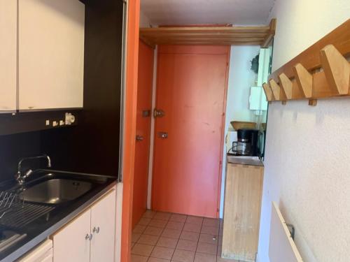 - une cuisine avec une porte rouge et un évier dans l'établissement Studio skis aux pieds, 4 pers, balcon sud, cœur des Menuires - FR-1-452-185, aux Menuires