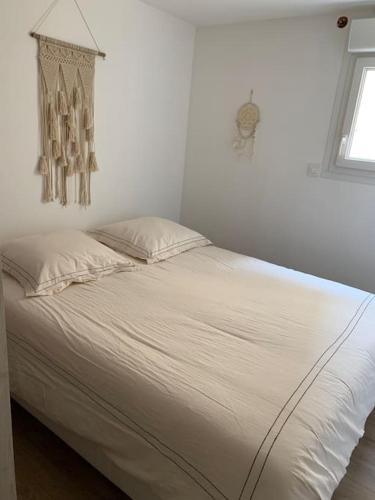 - un lit blanc dans une chambre avec fenêtre dans l'établissement Appartement T2 à Sanary-sur-Mer, à Sanary-sur-Mer