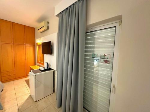 a bathroom with a shower curtain and a refrigerator at Castro Hotel in Amoudara Herakliou
