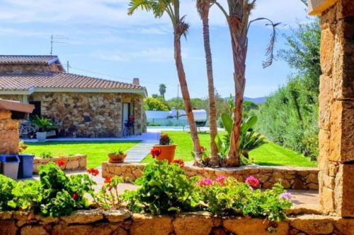 a garden with palm trees and a house at splendido open space in Villa Veronica Porto Istana in Porto Istana