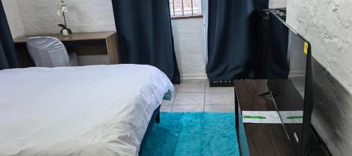 a bedroom with a bed and a desk and a window at Calming Waters Guesthouse in Grahamstown