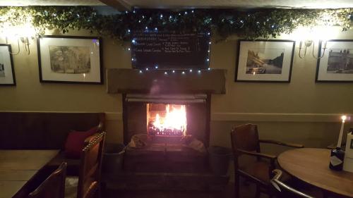 a fireplace in a restaurant with a table and chairs at The Cavendish Arms in Cartmel