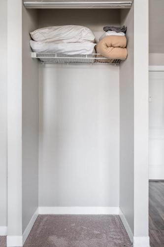 a closet with white walls and a shelf with towels at Spacious 2BR Apt on Mass Ave w Kitchen in Indianapolis