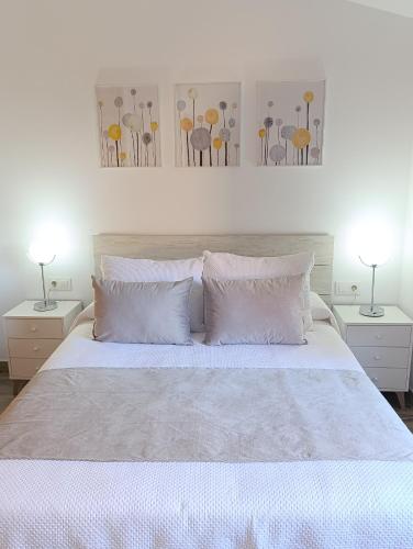 a bedroom with a white bed with two tables and two lamps at El Cantillo del Jerte in Cabezuela del Valle