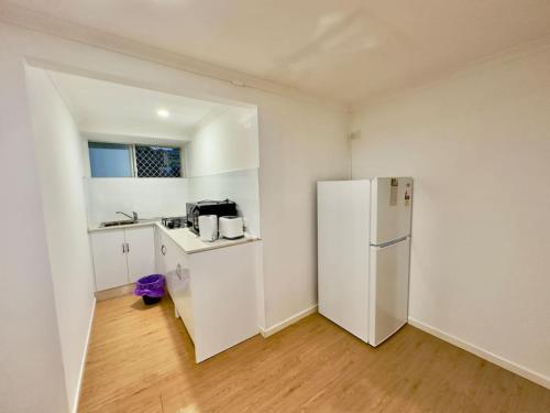 a kitchen with a white refrigerator and a wooden floor at Prime 1BR Near Transport and Retail in Brisbane