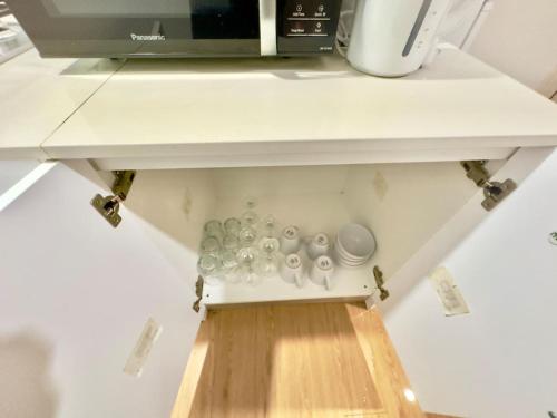 a kitchen counter with a shelf with cups and a microwave at Prime 1BR Near Transport and Retail in Brisbane