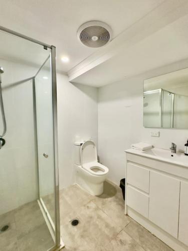 a bathroom with a toilet and a shower and a sink at Prime 1BR Near Transport and Retail in Brisbane