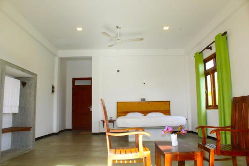 a bedroom with a bed and a table and chairs at CPS Lihini Beach Hotel in Induruwa