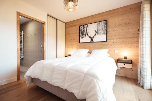 une chambre avec un grand lit blanc et des murs en bois dans l'établissement Appartement Margot - All the comforts with a view of Mont Blanc, à Combloux