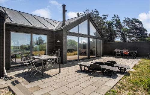 a patio with a table and chairs and windows at Lovely Home In Blokhus With Sauna in Blokhus
