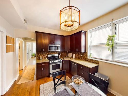 a kitchen with wooden cabinets and a chandelier at Chi-Town Hideout #1 in Berwyn