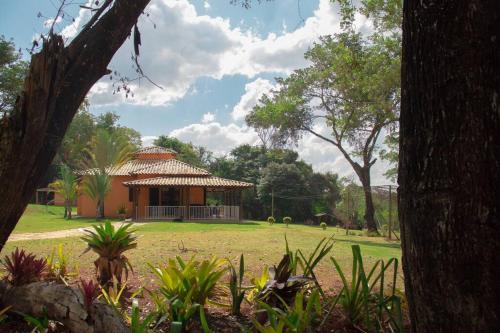 a small house with a thatched roof in a park at Sítio mini fazenda em Lagoa Santa in Lagoa Santa