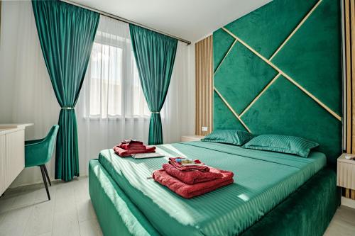a bedroom with a green bed with two towels on it at FLH - Robella Apartment in Sibiu