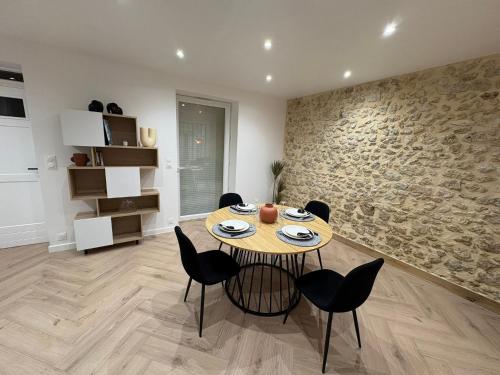 une salle à manger avec une table et des chaises et un mur en pierre dans l'établissement Chez Sof&Jé, à Brie-Comte-Robert