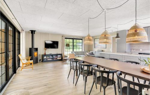 a kitchen and living room with a long table and chairs at Nice Home In Hvide Sande With Sauna in Bjerregård