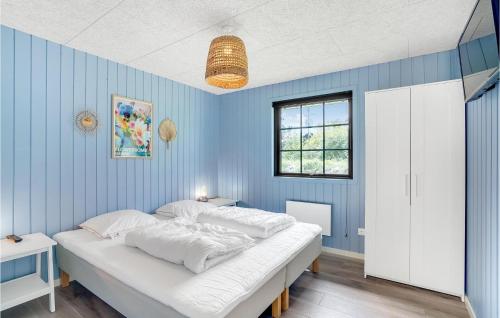 a bedroom with a large bed in a blue wall at Nice Home In Hvide Sande With Sauna in Bjerregård