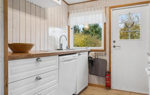 a kitchen with white cabinets and a window and a sink at Nice Home In Bogø By With Wifi in Bogø By