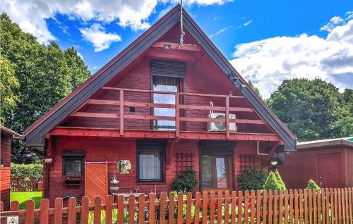 a red house with a fence in front of it at 2 Bedroom Amazing Home In Wilcze in Wilcze