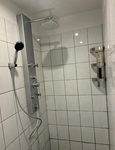 a shower in a bathroom with white tiles at Apartment nah Flughafen, Messe, Arena, Dome in Düsseldorf
